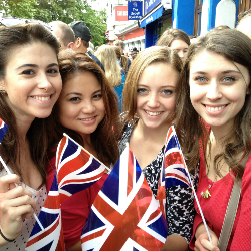 Four study abroad students in the United Kingdom holding UK flags