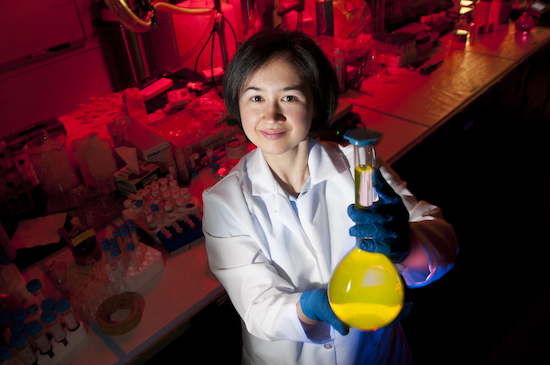 ""Student holding a beaker with yellow liquid in it.