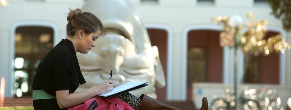 Student studying outside next to egghead sculpture