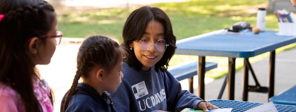 Smiling children at outdoor blue picnic table reading picture books