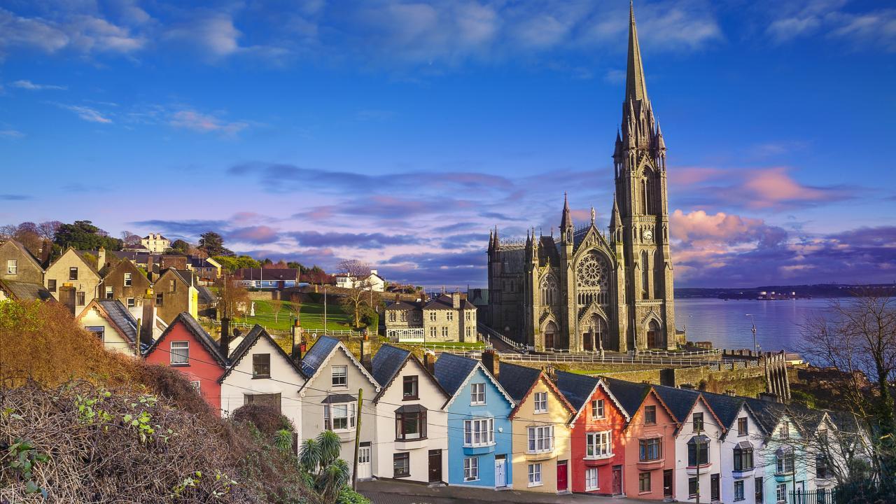 Colorful seafront rowhouses with tall church spire at sunset