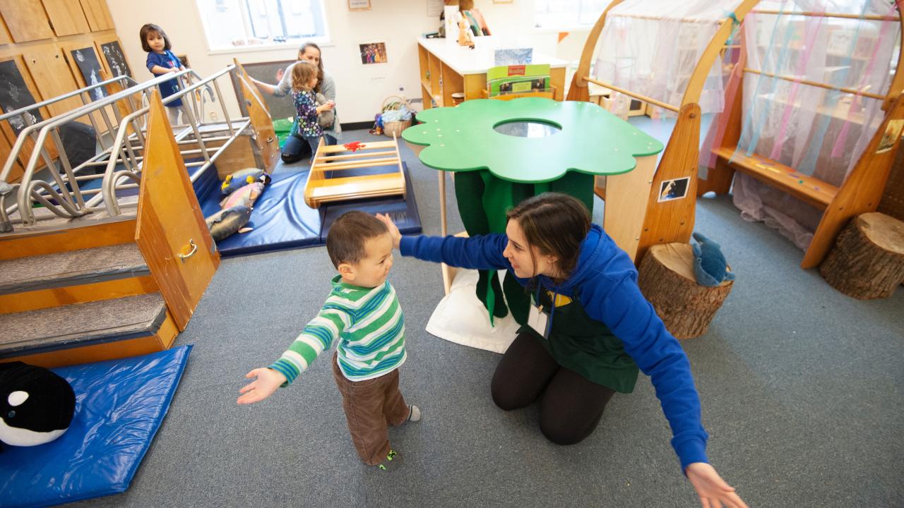 A student plays with a child at the campus childcare center