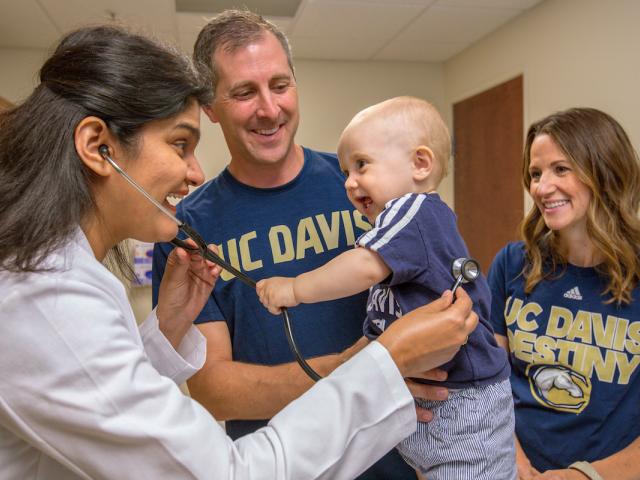 Doctor treating small child with parents smiling
