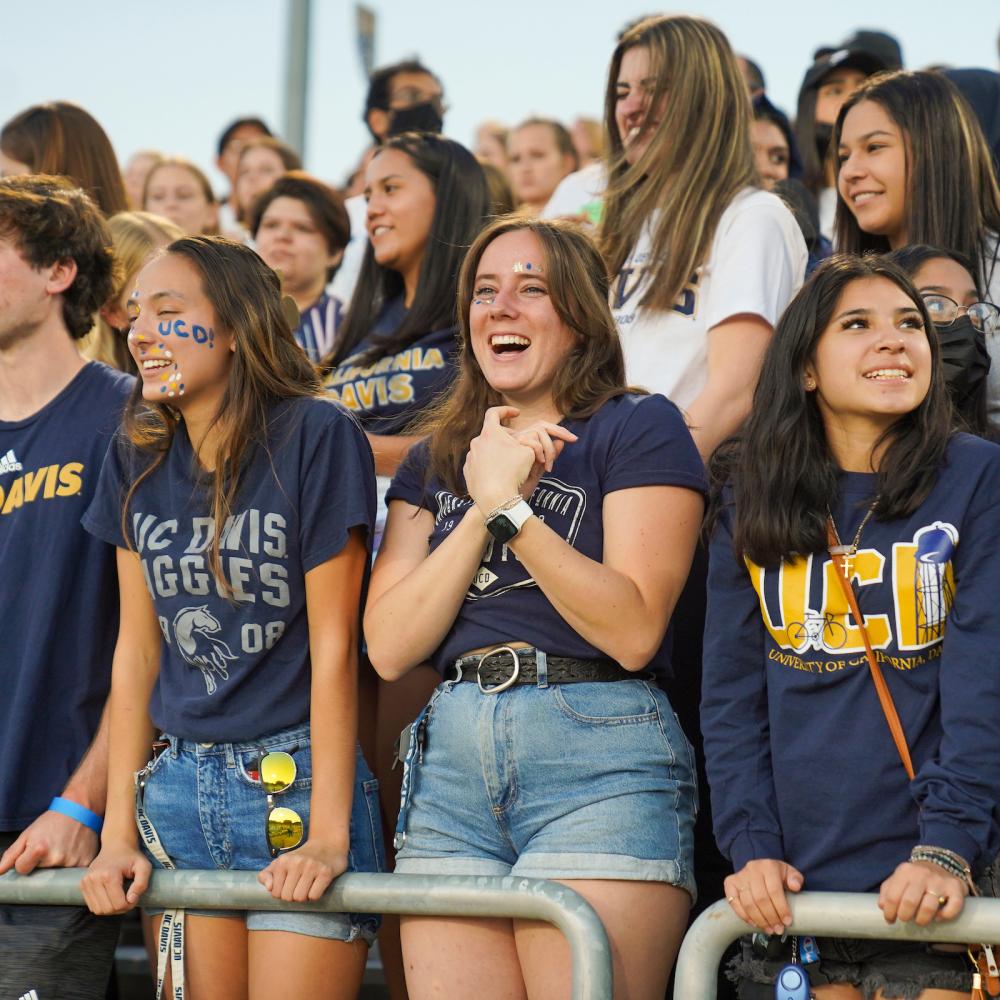 Students attending an outdoor sporting event, standing at a railing