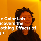 A student participates in a color experiment with amber light in the background.