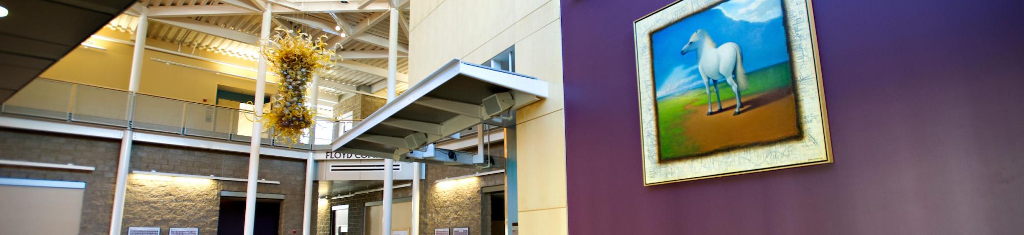 The interior of the veterinary school; a purple wall with a painting of a horse faces a reception desk