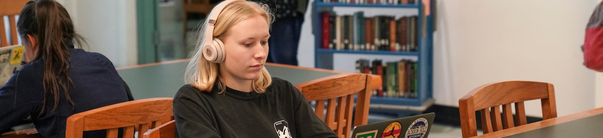 Student with laptop at a library table