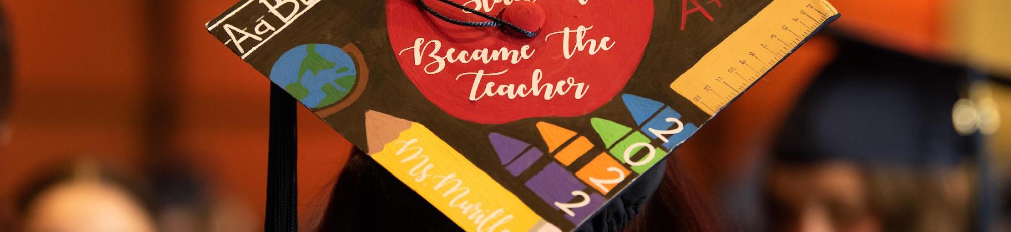 Close-up of a mortar board decorated with an apple and school imagery.