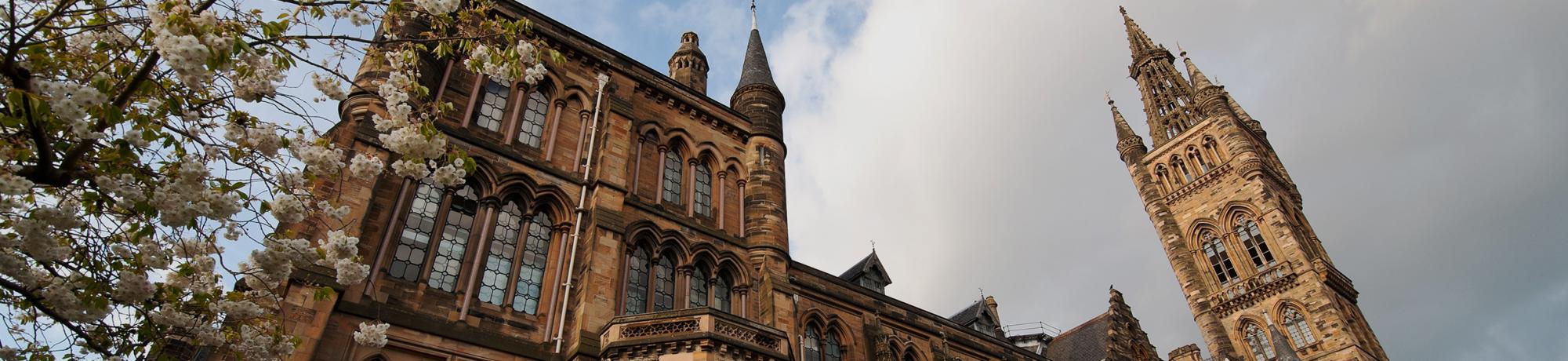 Low-angle photo of ornate brownstone building with a tall clock tower under cloudy sky